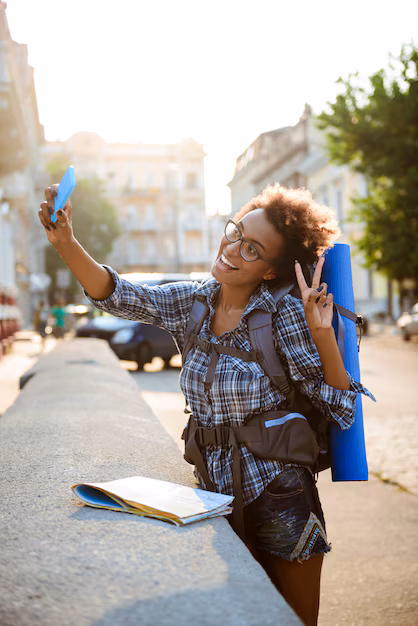 young-beautiful-african-female-traveler-with-backpack-smiling-making-selfie_176420-6910